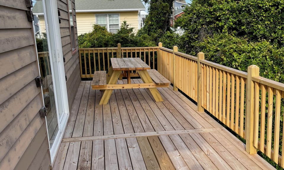 Step onto your private wooden deck featuring a picnic table perfect for outdoor dining surrounded by lush trees.