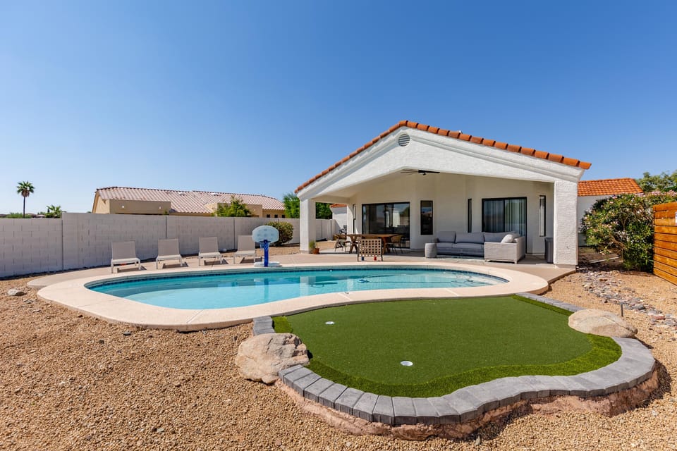 Sparkling heated pool, putting green, fire pit, sun loungers, BBQ, cornhole, and outdoor patio furniture, plus dining area.