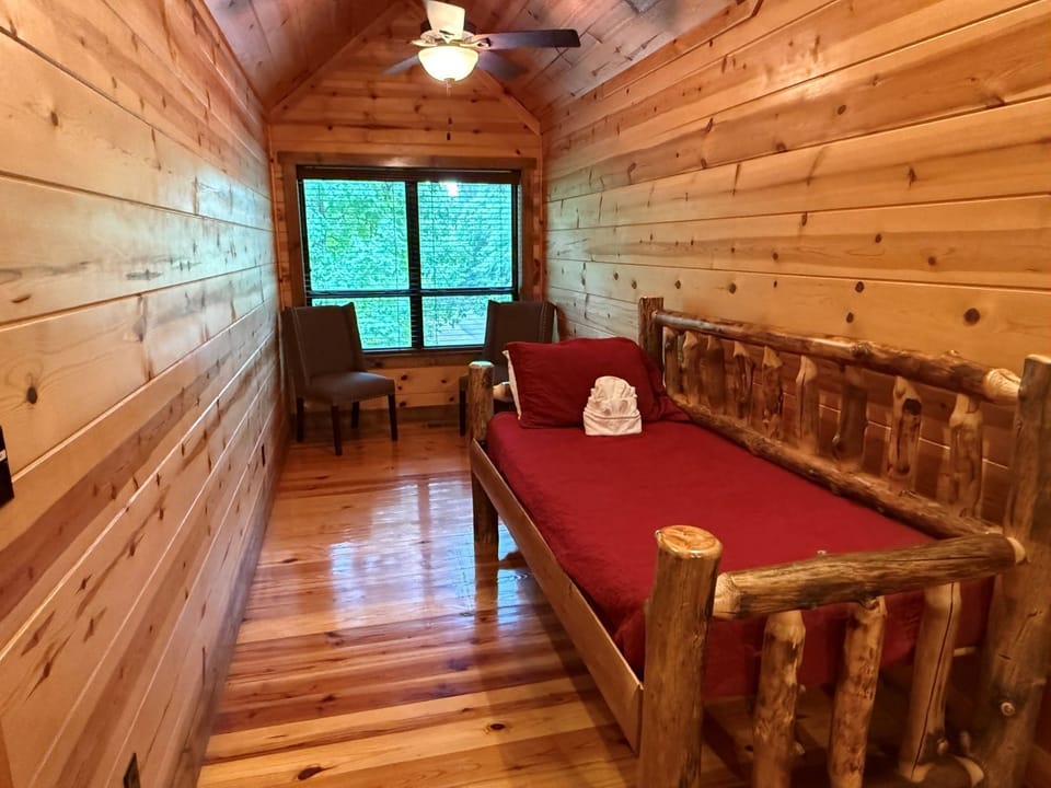 Your cozy retreat features rustic log furniture, warm pine walls, and a peaceful view of greenery—a perfect place to unwind after exploring the day's adventures.