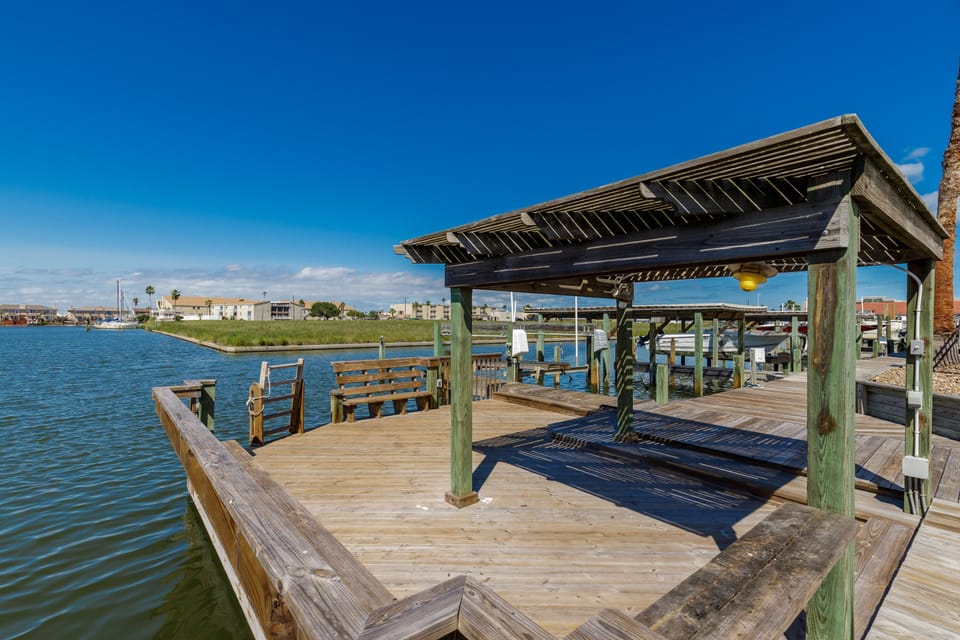 Waterfront dock with covered pavilion and boat slips, offering direct bay access for fishing and boating activities.