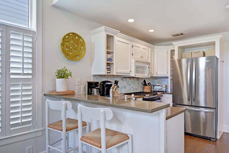 Full Kitchen with Stainless Appliances - Kitchen includes stainless appliances, white cabinetry, prep space, and bar seating for breakfast or takeout.