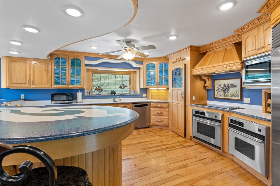Chef-style commercial kitchen with double ovens, oversized fridge, and seating, built for large group meals and entertaining.
