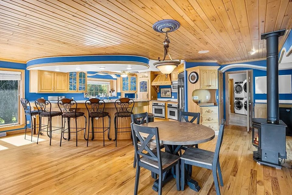 Bright chef-style commercial kitchen with double ovens, oversized fridge, and seating, built for large group meals and entertaining.