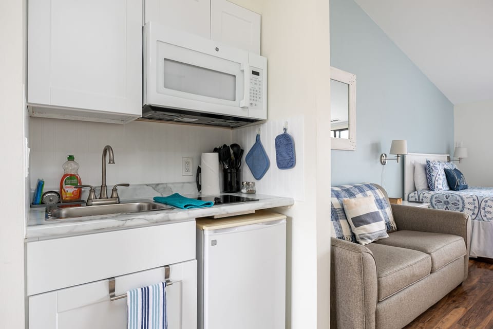 A compact kitchenette equipped with a mini fridge and microwave, offering a convenient setup. Overlooking the room adorned with a queen-size sleeper sofa and a comfortable queen-size bed.
