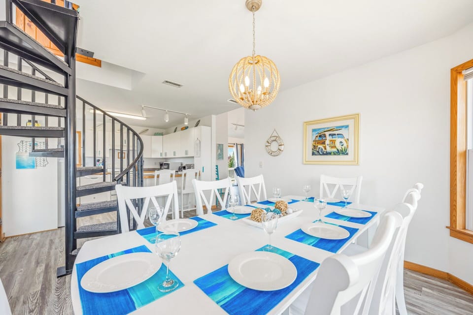 Gather loved ones around the elegant dining table, styled with coastal flair, beneath a statement chandelier—perfect for memorable meals and celebrations together.