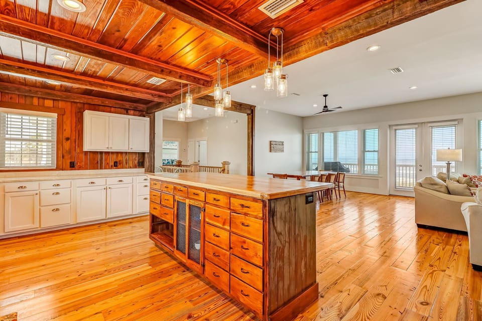 Spacious Fully Equipped Luxury Kitchen with Stainless Steel Appliances, A Large Butcher Block Island, Bar Stool Seating, and Beautiful Heart Pine Wood Walls and Beams