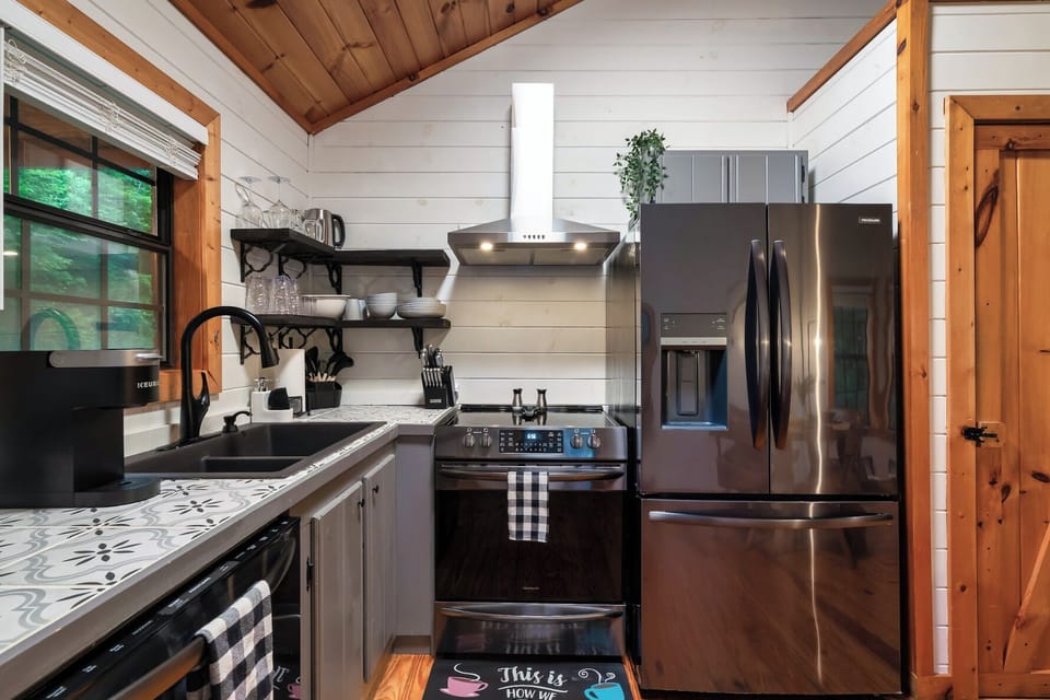 Modern cabin kitchen—black stainless appliances, open shelves, coffee station.