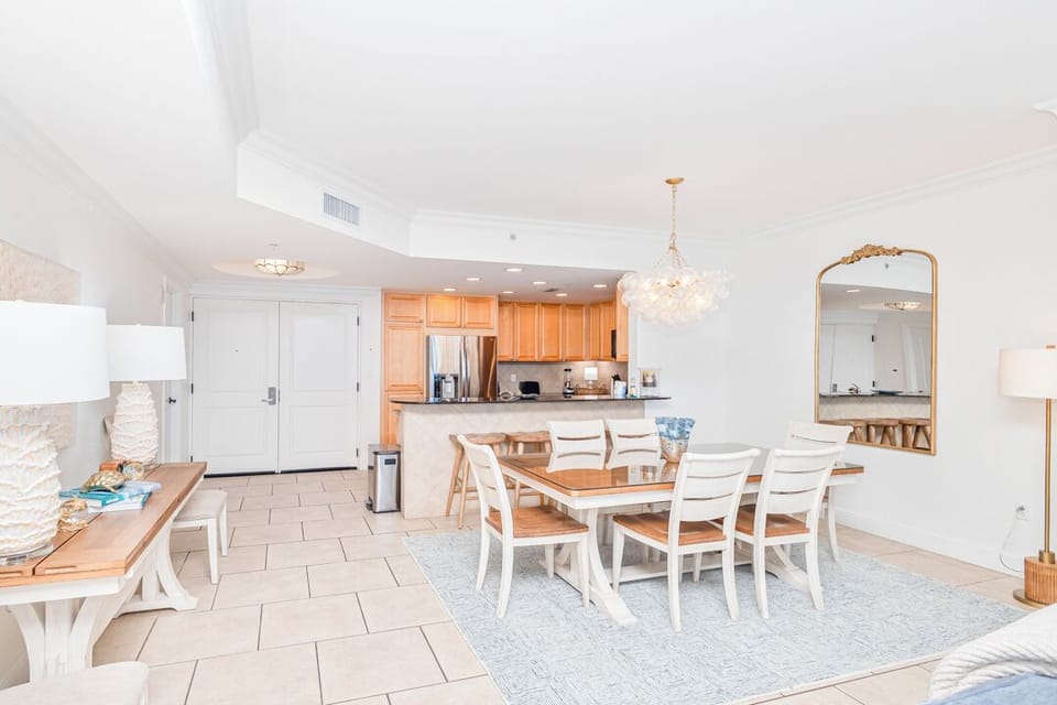 Gather around the elegant dining table under a sparkling chandelier, with the open kitchen ready for your vacation meals. This bright, airy space invites you to share laughter and stories with your favorite people.