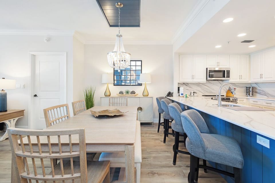 Your open-concept kitchen and dining flows seamlessly together, featuring a sparkling chandelier overhead and comfortable seating at the stunning blue island.