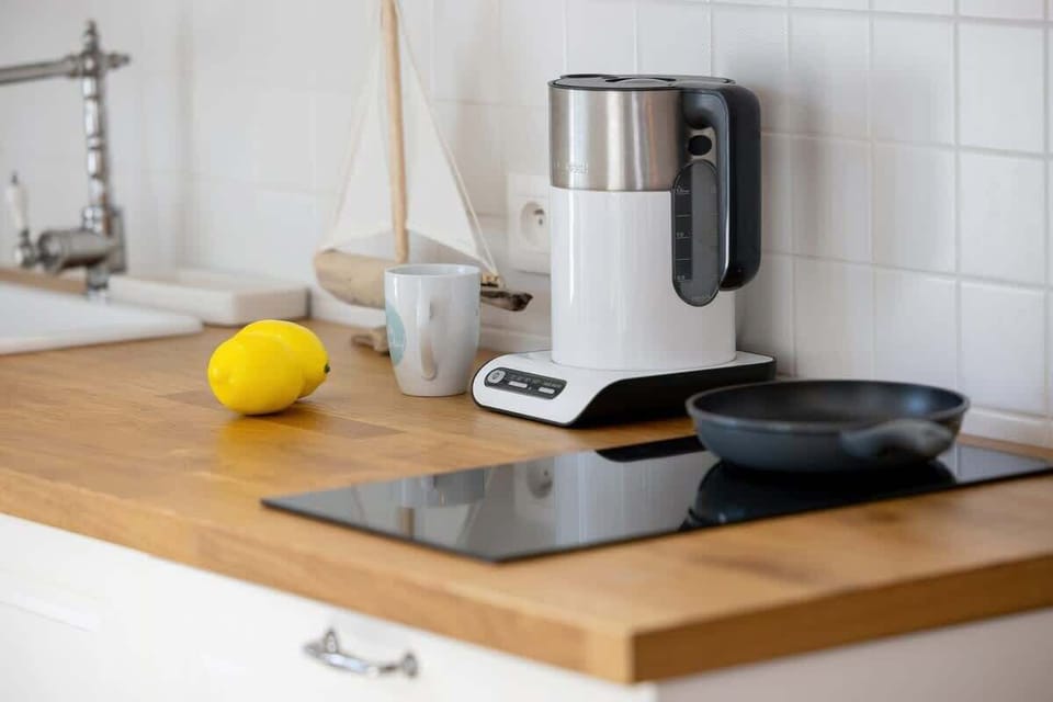  A modern kitchen with a wooden countertop and appliances, featuring a lemon and a blender for decor