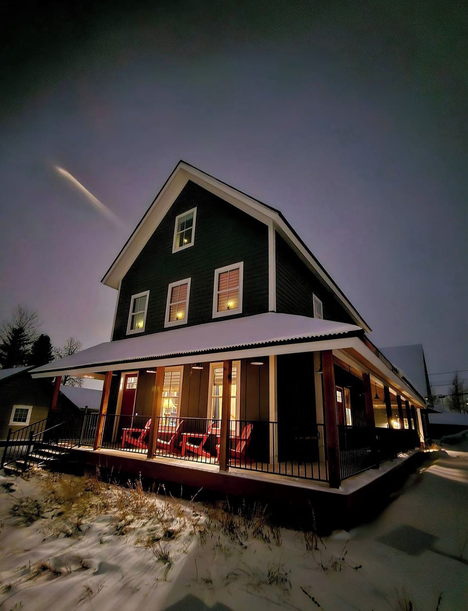 Shooting star at dusk with warm light glowing from inside the house.