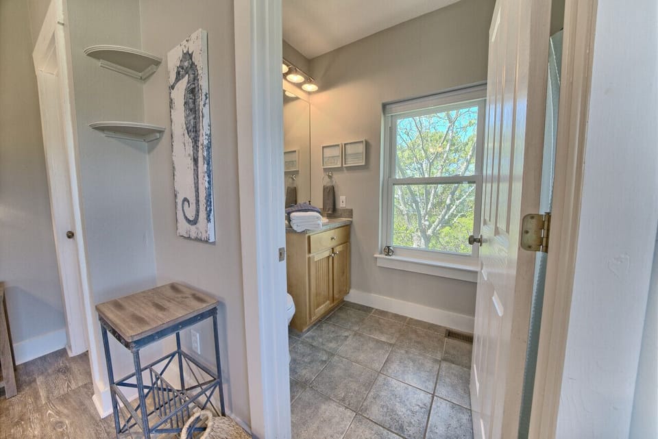 Full bathroom with a single vanity, ample mirror, and bright window. Practical for families, well-maintained and clean.