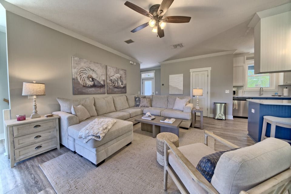 Comfortable living room features a large sectional sofa, coffee table, and ceiling fan. Open concept to kitchen for easy flow.