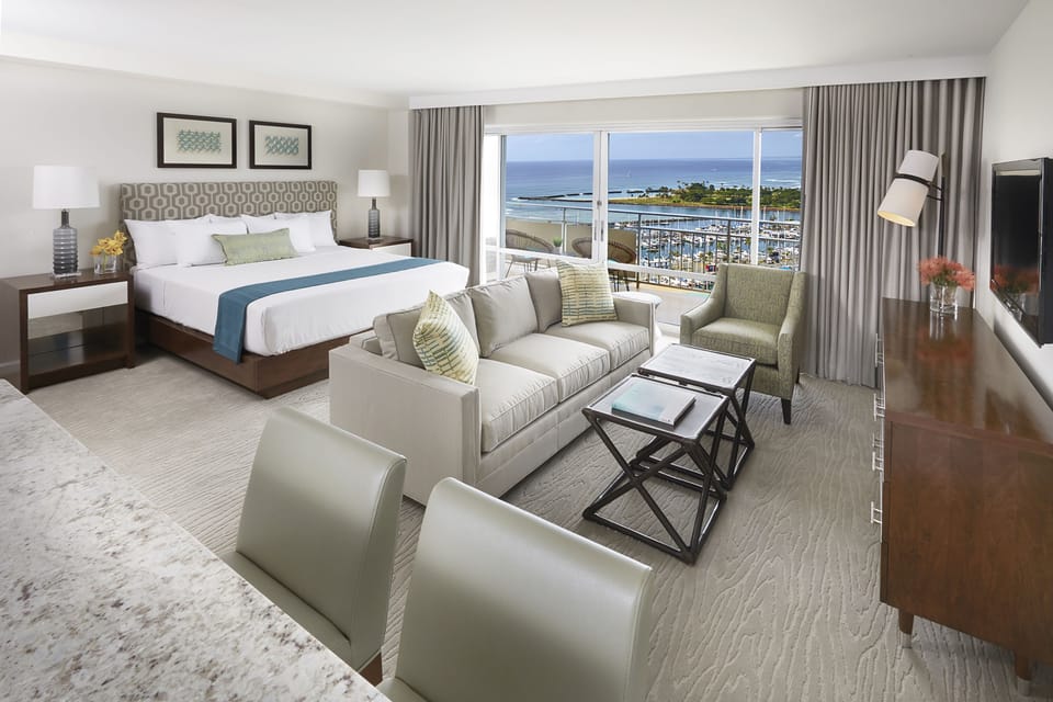 Unwind in your spacious suite with plush bedding, a cozy seating area, and breathtaking ocean views through your private balcony doors—your perfect coastal retreat awaits.