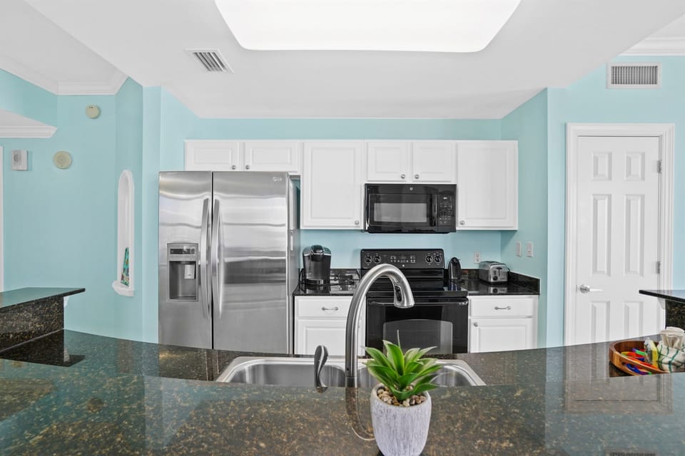 Prepare delicious meals in your fully equipped kitchen featuring stainless steel appliances, granite countertops, and refreshing coastal-inspired decor.