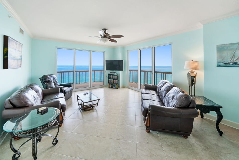 Unwind in your oceanfront living room with panoramic sea views. Comfortable leather seating and ceiling fan create the perfect coastal retreat.