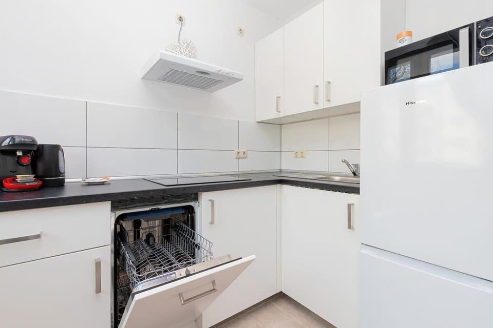 Close-up of the open dishwasher in the kitchen. A microwave oven sits on the fridge.