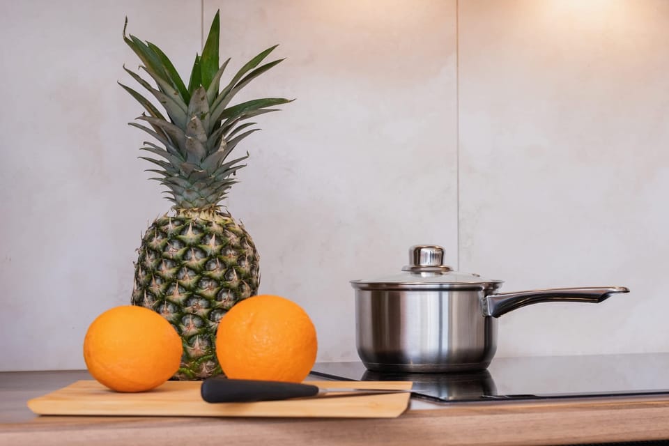 A close-up showing a pineapple, and cooking utensils on a modern kitchen counter.