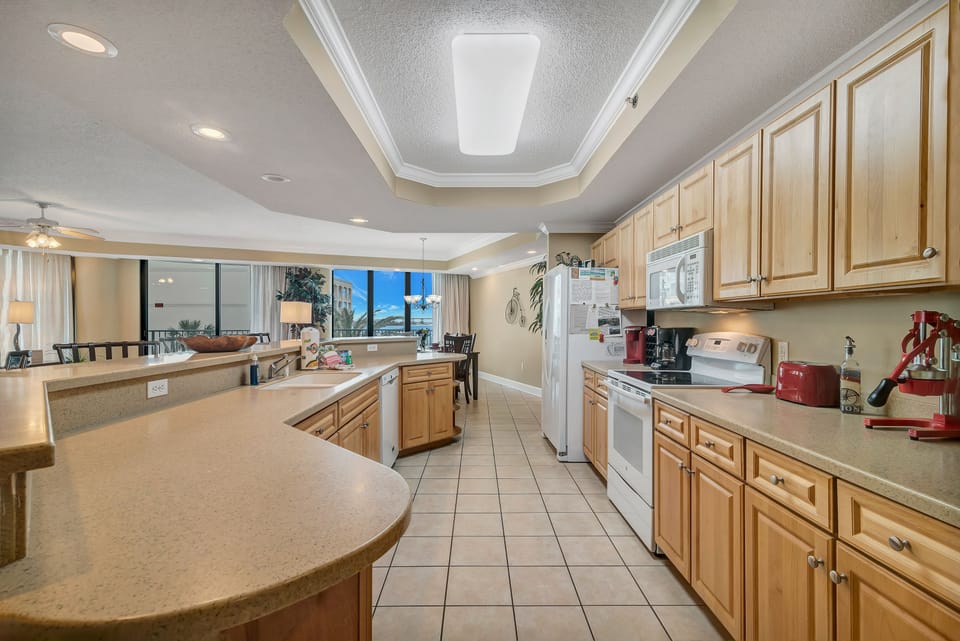 This well-appointed kitchen features essential appliances, including a range and microwave, plenty of light-wood cabinetry and spacious counters. Enjoy the convenience of a dedicated coffee station, offering both a Keurig and a classic drip coffee maker.