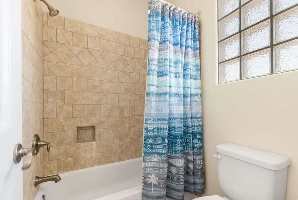 Bathroom — Tub/Shower with Travertine Tile, Beach-Themed Curtain & Glass Block Window