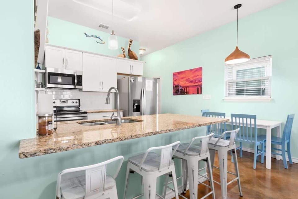 Kitchen & Dining — Granite Breakfast Bar, White Metal Stools, Stainless Appliances, Sunset Canvas & Blue Dining Table