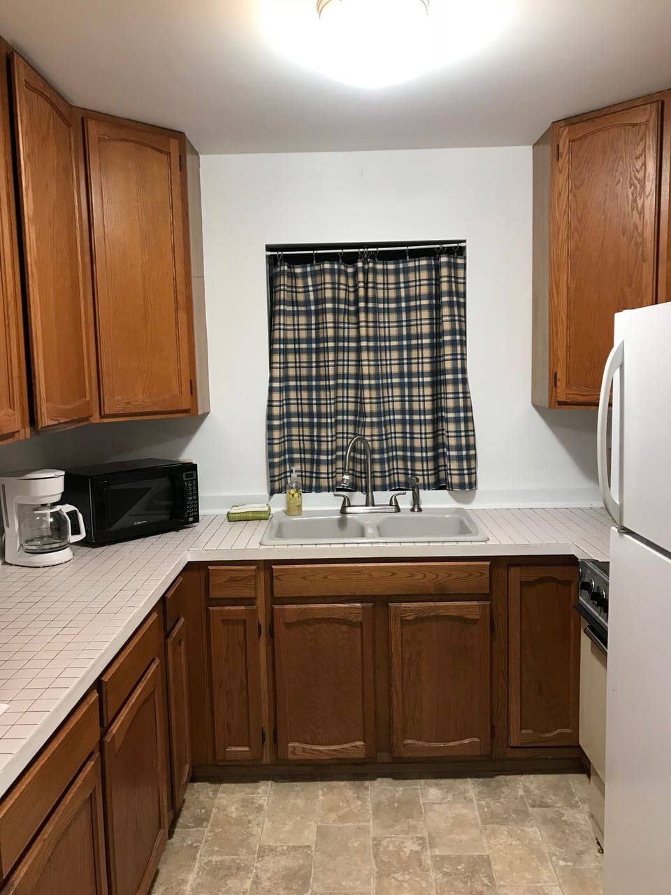 Kitchen features refrigerator, oven/range, microwave, and basic cooking items. 