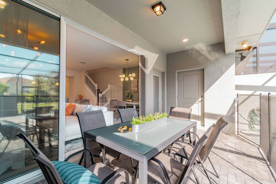 Step outside to a spacious balcony featuring sleek outdoor furniture, perfect for al fresco dining. The warm natural light pours in, highlighting the contemporary design and inviting atmosphere just beyond the glass doors.