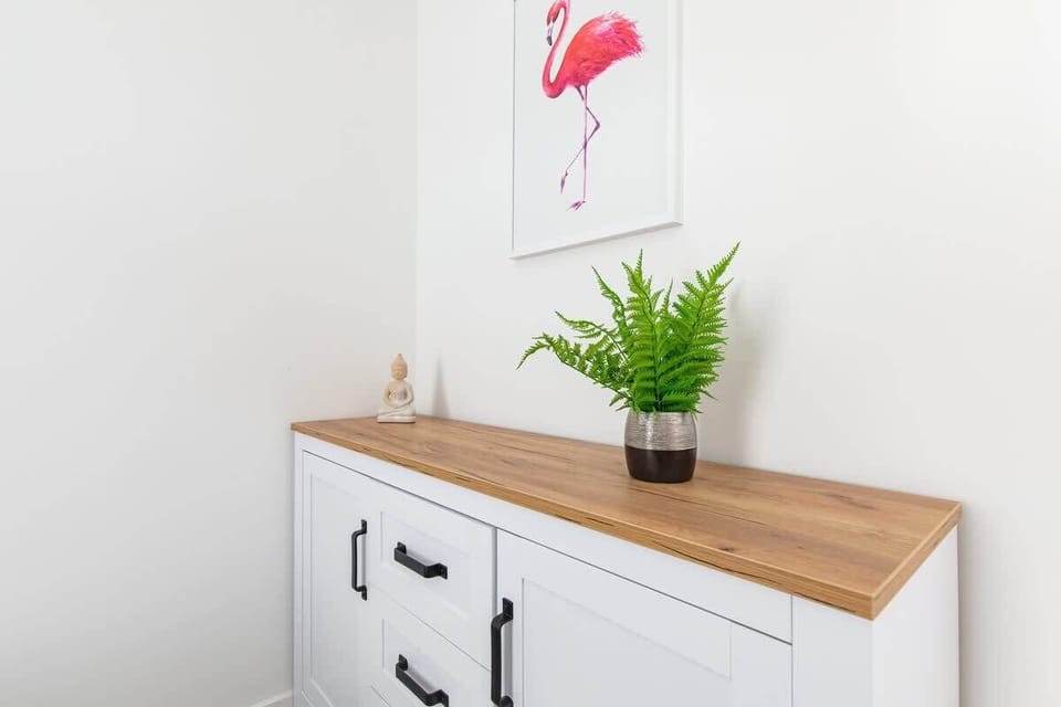 Close-up of the dresser in the bedroom. The chest of drawers is white with a wooden top.