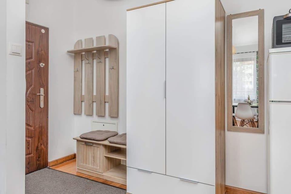A hallway or interior shot with built-in closets, a bench, and mirrors, leading to the living area.