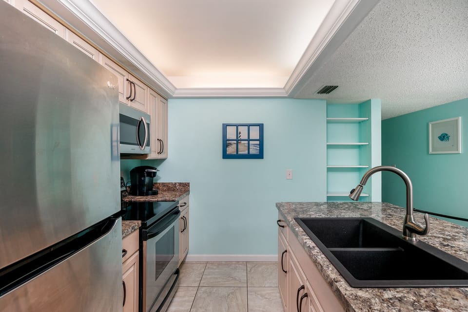 Fully Equipped Kitchen: Prepare meals and coffee easily! This kitchen features stainless steel appliances, a coffee maker, and ample counter space for your vacation needs.