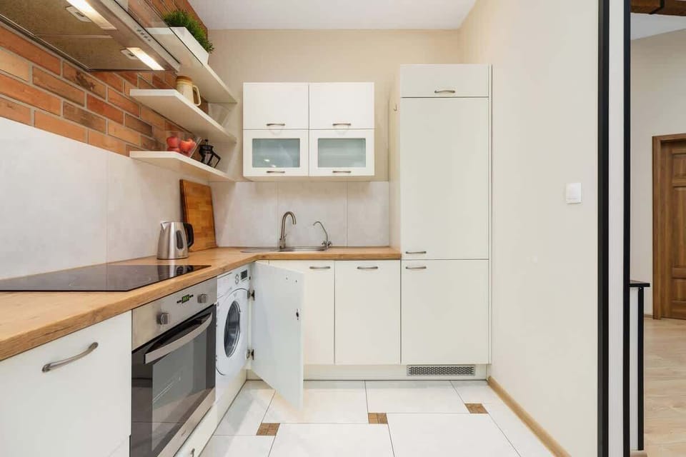 Bright kitchen with quality appliances such as oven, induction hob, fridge, electric kettle and washing machine.