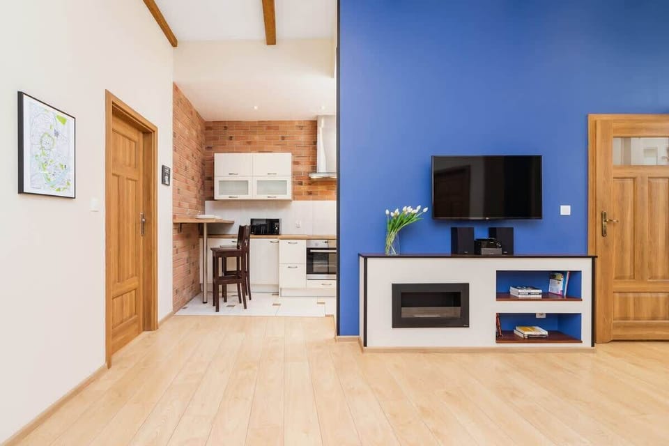 Spacious bright living room which is made cosy by the revolved elements and soft carpet. A flat-screen TV hangs on the blue wall.