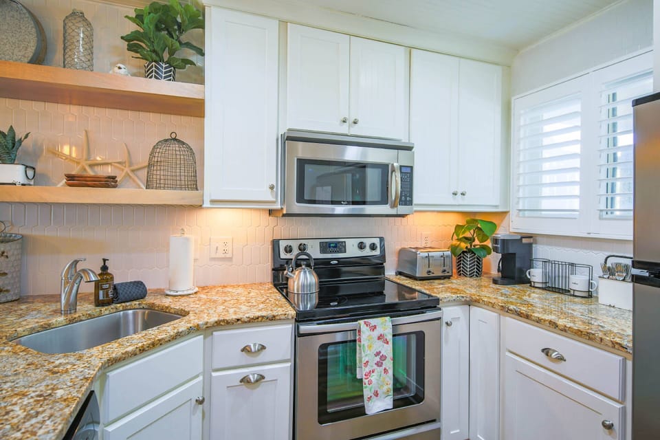 The kitchen features a new tiled backsplash, white cabinets and stainless steel appliances.