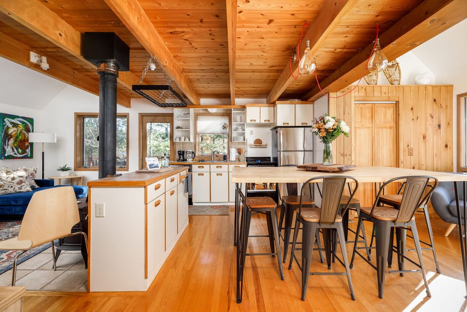 Warm dining area w/ wood beams, large table & open flow to kitchen