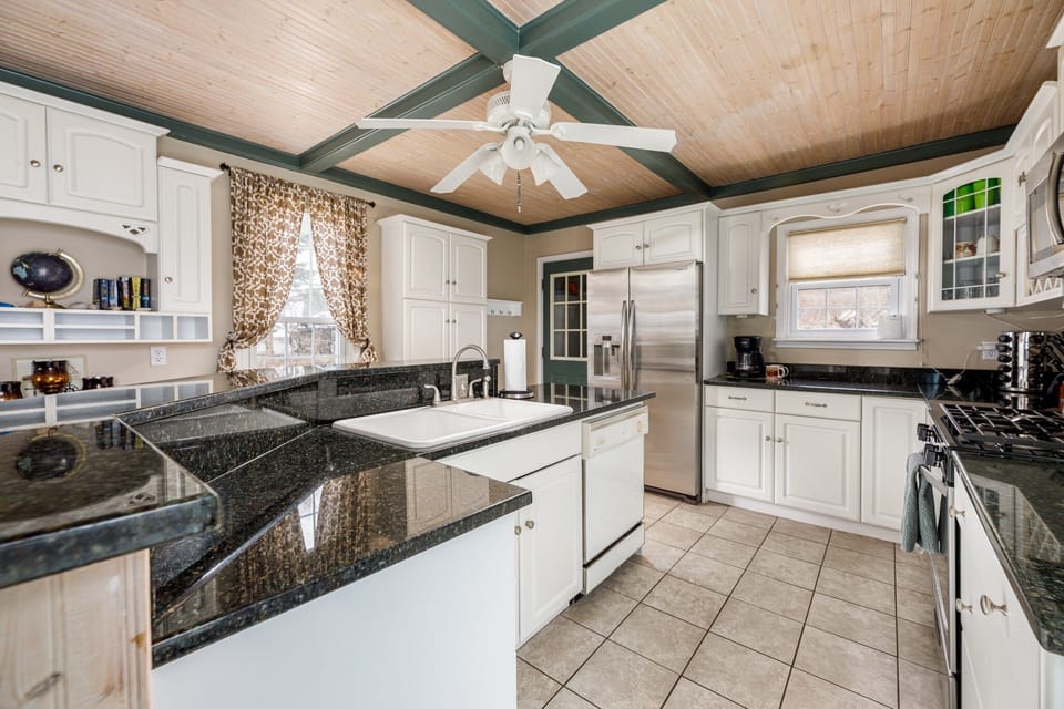 Spacious kitchen w/ granite counters, white cabinetry & stainless steel appliances.