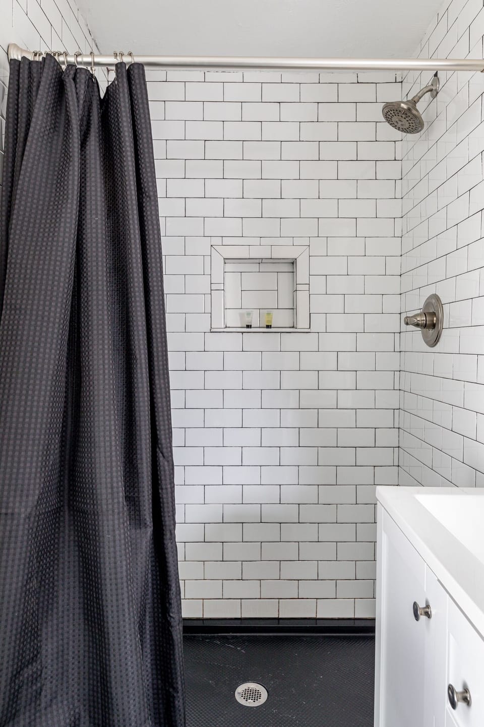 Tiled shower & tub combo w/ sleek fixtures & crisp white subway walls.