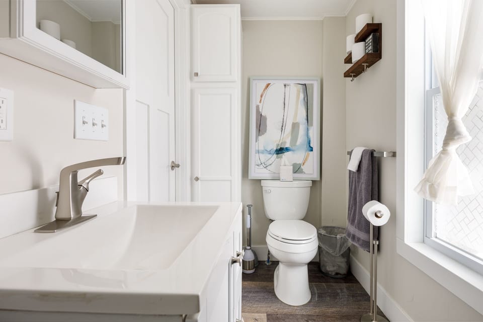 Full bath w/ tub & shower combo, modern vanity & simple, airy design.