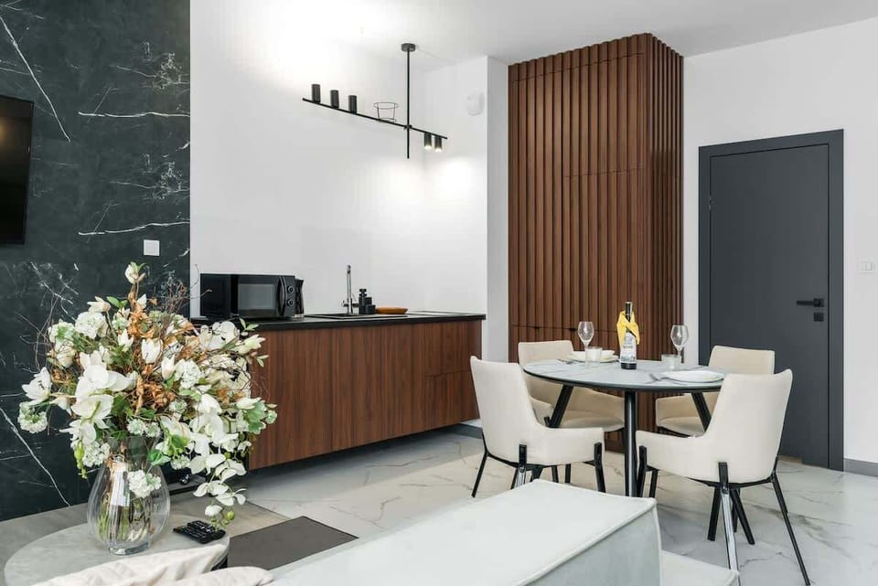 Harmonious combination of functional kitchen with dining area with table and chairs.