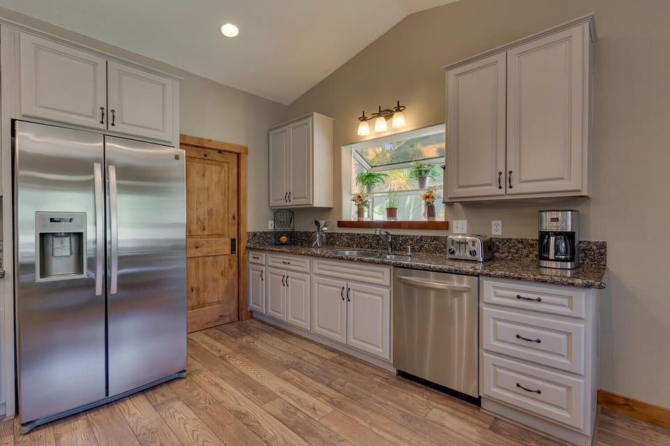 - Fully stocked kitchen with modern stainless steel  
- Ample cabinet space and large granite counters  
- Bright and open with window views of the pines