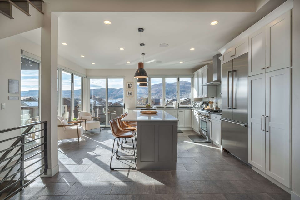 The open kitchen has modern stainless appliances and seating for four at the breakfast bar