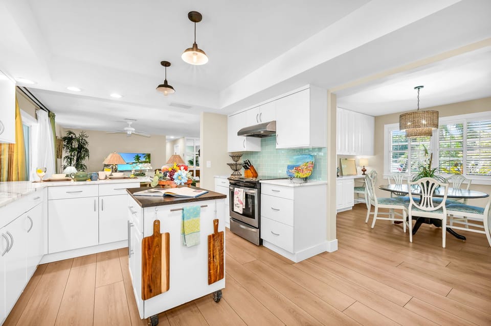 The impressive kitchen is complete with stainless steel appliances and double stainless fridge, a gorgeous aqua tile backsplash, white elegant cabinets, and an island for additonal cooking preparation.