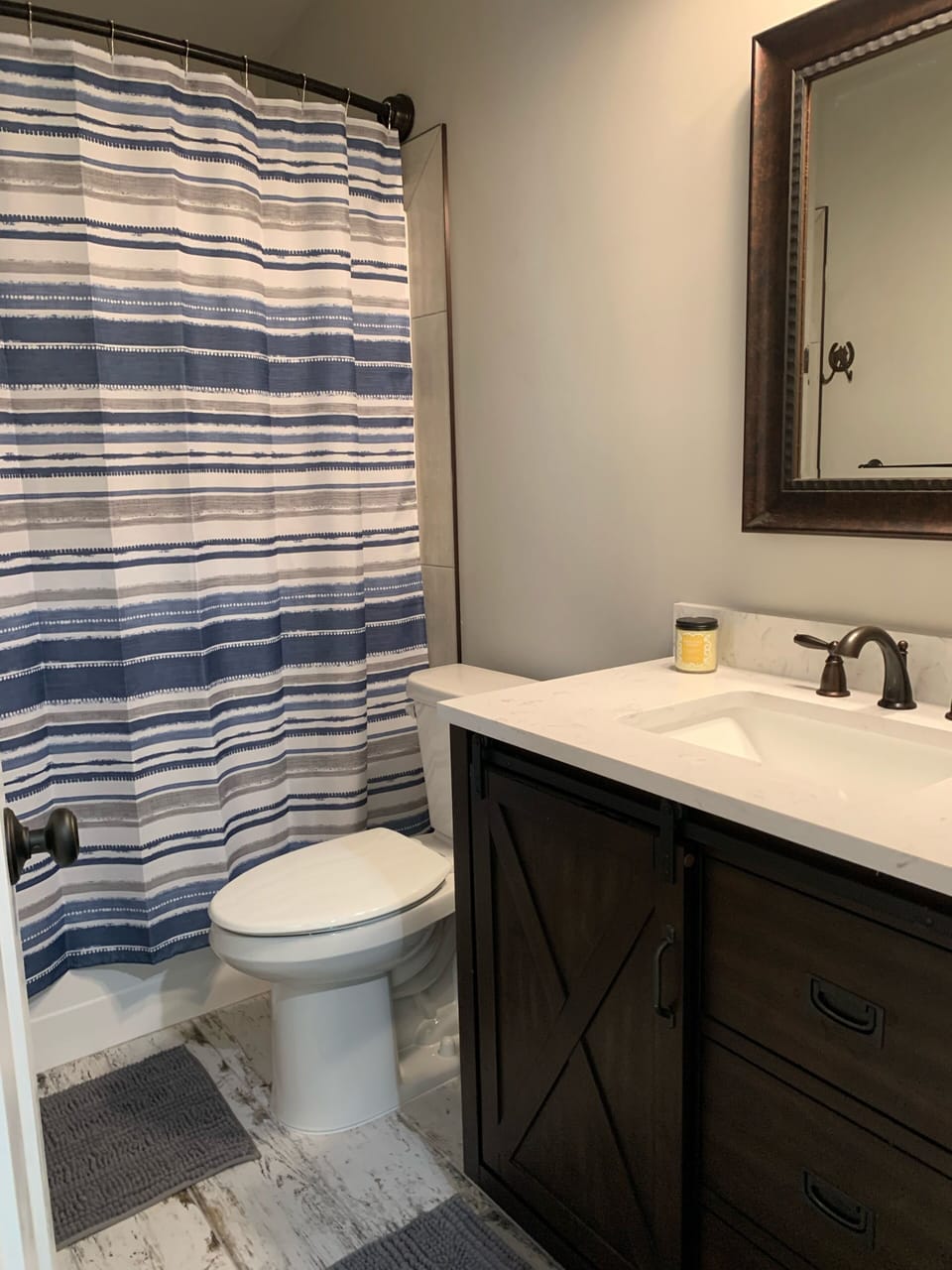 Pocket door to bedroom, tub-shower unit,  urban style vanity with large mirror.