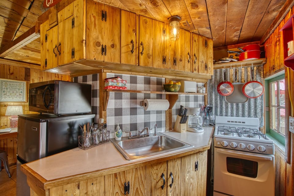 Featuring a well stocked vintage kitchenette including gas stove, microwave, minifridge & freezer, toaster, coffee maker, along with basic oils and spices, dishes and cookware.