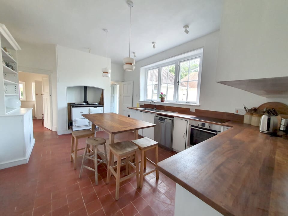 The kitchen, with dresser, island, electric hob and oven and Aga