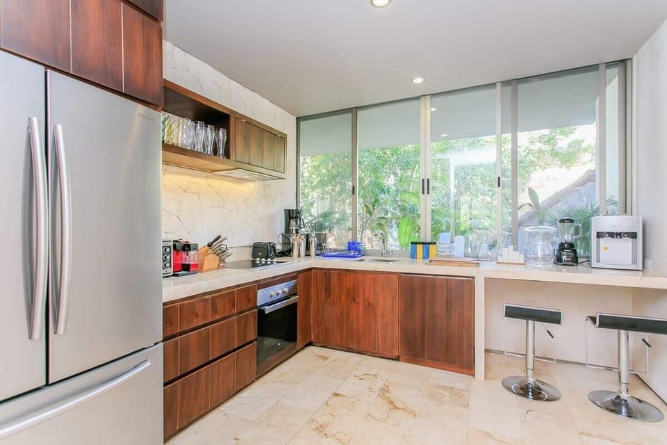 Modern kitchen with wooden cabinetry and large windows overlooking greenery