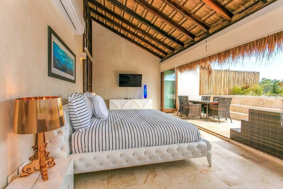 Modern bedroom with a thatched roof and an open terrace seating area