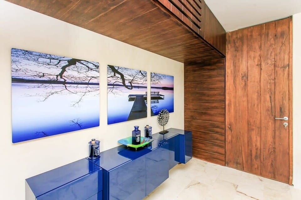 Modern entryway featuring a glossy blue console and nature-inspired wall art.