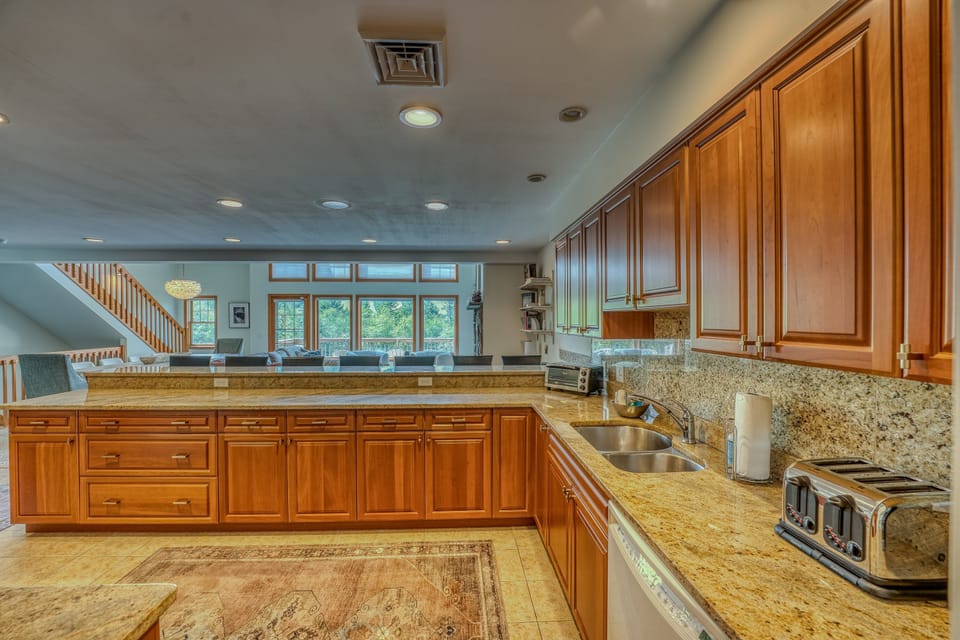 The fully stocked kitchen features warm wood cabinetry, modern appliances, and a large breakfast bar with seating for six