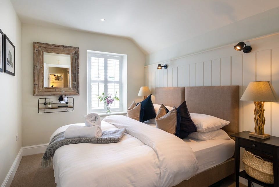 Super-king bedroom with tufted grey headboard and coastal navy cushions, pet-friendly apartment above The White Eagle, Rhoscolyn, Anglesey