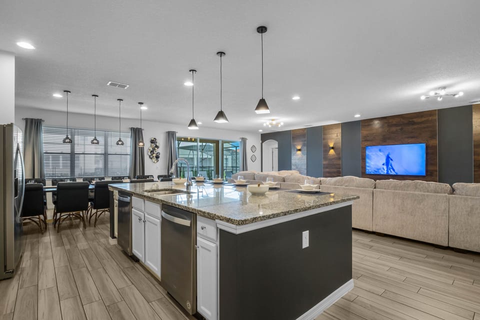 - Spacious kitchen with granite countertops and pendant lights  
- Open-concept Orlando vacation rental perfect for big groups  
- Family gathering space with dining and entertainment area